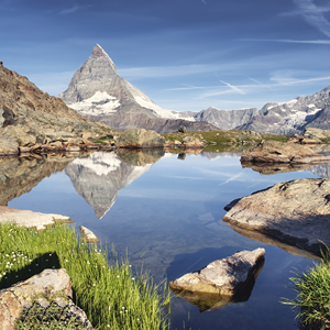 Beeindruckendes Matterhorn mit Spiegelung im Bergsee Das Matterhorn spiegelt sich in einem klaren Bergsee, umgeben von einer alpinen Landschaft und klarem Himmel.